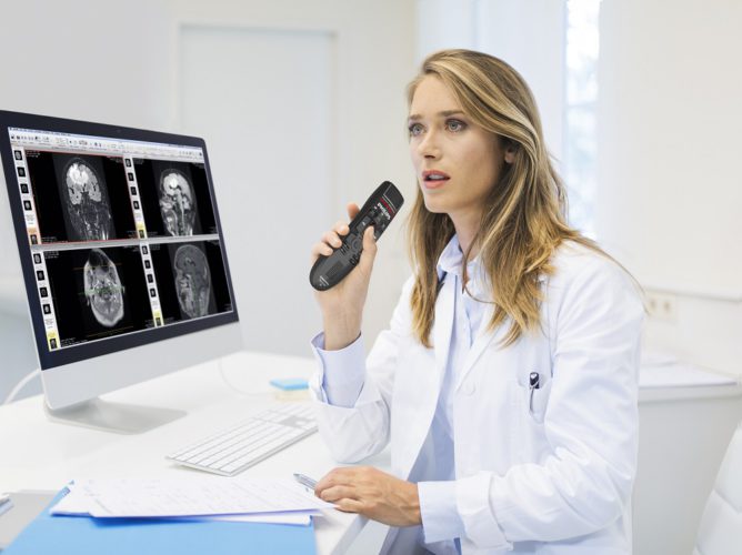 Medical Practitioner holding speechmike microphone to her mouth and dictating a medical diagnosis